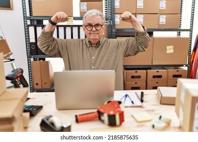 Senior Caucasian Man Working At Small Business Ecommerce With Laptop Showing Arms Muscles Smiling Proud. Fitness Concept. 