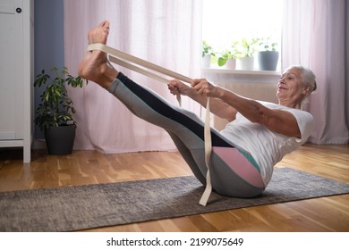 Senior caucasian woman doing abs exercises, sitting in boat yoga pose at home. Yoga at old age. - Shutterstock ID 2199075649