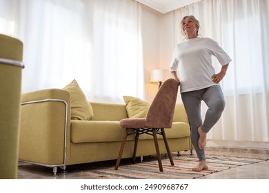 Senior caucasian woman doing yoga at home on chair - Powered by Shutterstock