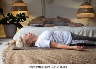 Senior Caucasian Woman Lying On Yoga Mat After Workout. Fit Female Relaxing On Floor At Home.