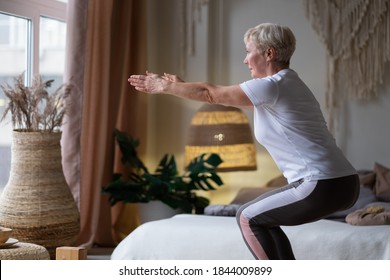 Senior Caucasian Woman Practicing Advanced Yoga Chair Pose Or Utkatasana At Home