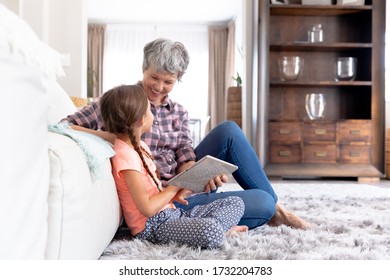 Senior Caucasian woman spending time at home together with her granddaughter, sitting on a couch in the sitting room and using a tablet. - Powered by Shutterstock