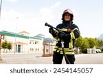 A senior Caucasian woman works as a firefighter dressed in a uniform.The adult woman looks at the camera happily while holding the water hose.Concept of women in risky professions.
