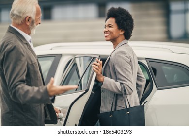 A Senior Chauffeur Opening A Car Door For Black Business Woman Before Their Business Trip.