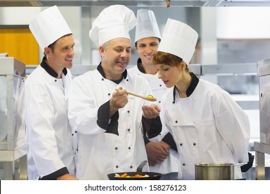 Senior chef showing food to his colleagues while being in the kitchen - Powered by Shutterstock