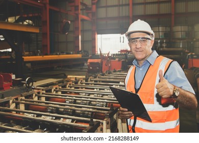 Senior Chief Engineer Wearing Goggles And Helmet Holding Clipboard Inspecting Machinery And Safety Systems Metal Sheet Factory Standing In Safe Working Area Showing Great Thumbs Up.