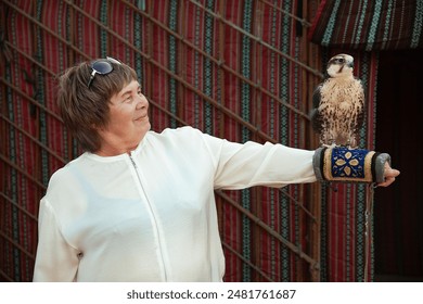 Senior citizen holds a falcon in the UAE desert - Powered by Shutterstock