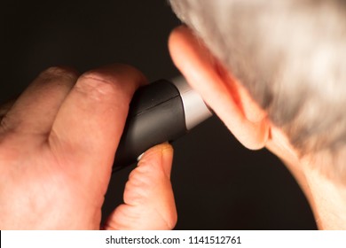 Senior Citizen Man Cutting Inner Ear Hair With Electric Cutter.