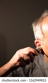 Senior Citizen Man Cutting Inner Ear Hair With Electric Cutter.