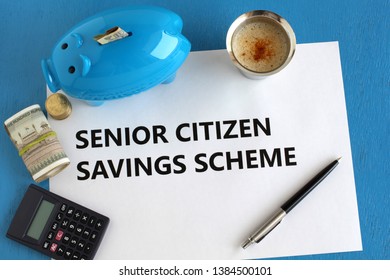 Senior Citizen Savings Scheme Concept Highlighted Through Text On Paper, Indian Rupees And Coins, Piggy Bank, Calculator, Pen And Coffee On A Blue Wooden Background.