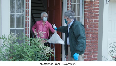 A Senior Citizen Using A Walker Who Is At High Risk Because Of The Coronavirus COVID19 Gets Meals Or Groceries Delivered To Her House By A Volunteer Working With A Benevolent Organization.