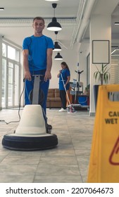 Senior Cleaner Cleans The Hard Floor With Machine While Cleaning Lady Cleans In The Backround