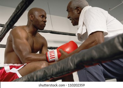 Senior coach advising boxer after the end of a round in the match - Powered by Shutterstock