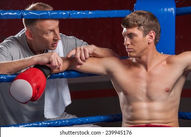 Senior Coach Advising Boxer After End Of Round. Two Man In Boxing Ring Talking