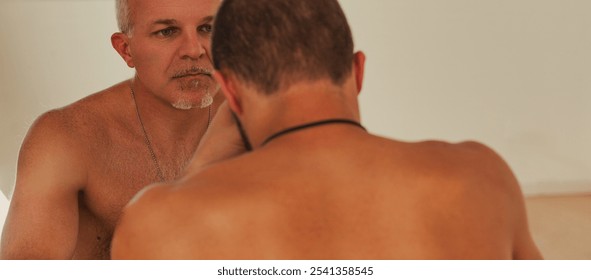 Senior coach is observing a young athlete looking at himself in the mirror, creating a powerful image of mentorship and self assessment in sports - Powered by Shutterstock