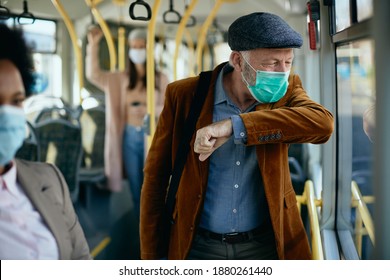 Senior commuter coughing into elbow while wearing face mask and traveling by public transport.  - Powered by Shutterstock