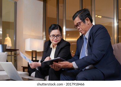 Senior company CEO showing tablet computer with annual report on screen to his colleague CFO at meeting