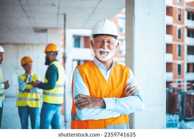 A senior construction site manager visually inspects a building project. Shot of a senior building contractor looking proud during a meeting. Smiling Chief Engineer with Tablet Reviewing Site - Powered by Shutterstock