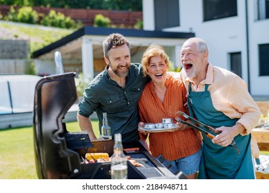 Senior couple with adult son grilling outside on backyard in summer family during garden party - Shutterstock ID 2184948711