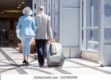 Senior couple in airport walking with suitcase. Holiday travel background. - Powered by Shutterstock