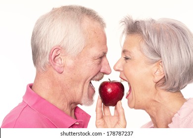 Senior couple with apple in front of white background