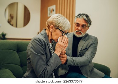 Senior couple argue in therapy. Mature spouses marriage counseling. Custody battle, divorce, alimony or family problem. Gray haired husband and wife meeting psychologist. Focus on a woman crying. - Powered by Shutterstock