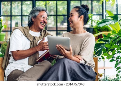 Senior couple asian family having good time using tablet computer together.Happy elderly husband and wife checking social media and reading news or shopping online while sitting at home - Powered by Shutterstock