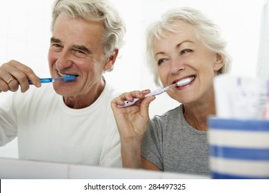 Senior Couple In Bathroom Brushing Teeth