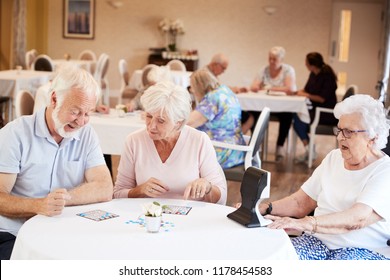 Senior Couple Being Served With Meal By Carer In Dining Room Of Retirement Home