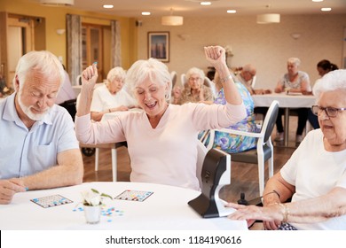 Senior Couple Being Served With Meal By Carer In Dining Room Of Retirement Home