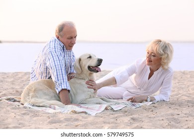 Senior couple and big dog sitting on plaid on riverside - Powered by Shutterstock