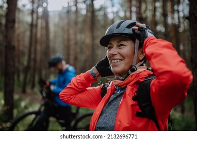 Senior couple bikers putting on cycling helmet outdoors in forest in autumn day. - Powered by Shutterstock