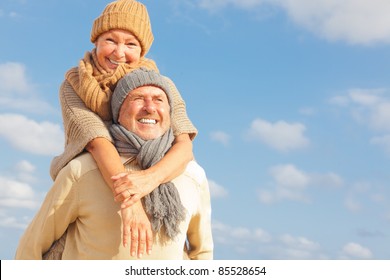 senior couple with blue sky in background having fun in autumn season on the coast in vacation - Powered by Shutterstock