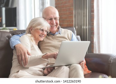 Senior Couple Browsing The Internet Together. Retirees Using A Laptop Computer At Home