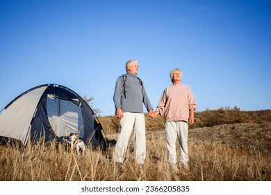 Senior couple of campers contemplating surrounding mountain scenery at cool sunny morning. Interesting adventure in the mountains. Concept of hiking, camping and relationships - Powered by Shutterstock