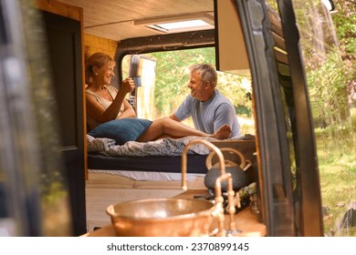 Senior Couple Camping In Countryside Relaxing Drinking Coffee Inside RV - Powered by Shutterstock