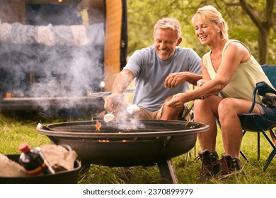 Senior Couple Camping In Countryside With RV Toasting Marshmallows Outdoors On Fire - Powered by Shutterstock