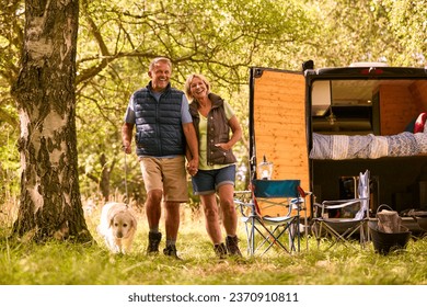 Senior Couple Camping In Countryside With RV Taking Labrador Dog For A Walk - Powered by Shutterstock