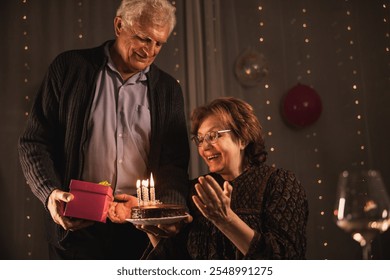 A senior couple celebrates a birthday with a chocolate cake topped with candles.  - Powered by Shutterstock