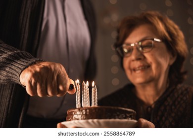 A senior couple celebrates a birthday with a chocolate cake topped with candles.  - Powered by Shutterstock