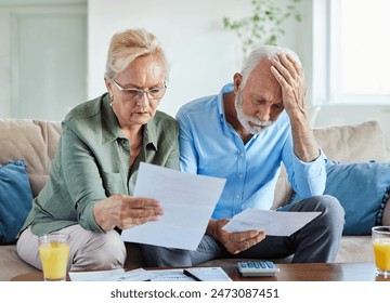 Senior couple checking bills and calculating expenses using a calculator at home, debt taxes and home budget concept, worried married elderly couple  - Powered by Shutterstock