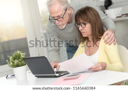 Senior couple checking financial document at home