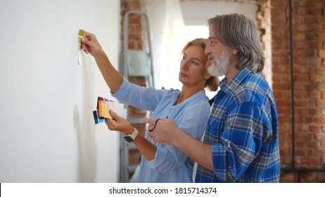 Senior Couple With Color Swatch Choosing Painting For New Home. Retired Husband And Wife Selecting Color For House Redecoration. Elderly Man And Woman Doing House Improvement