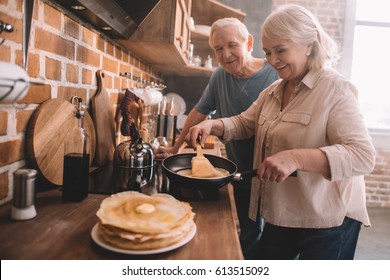 Senior Couple Cooking Pancakes On Kitchen At Home 