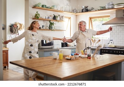 Senior Couple, Dance In Kitchen And Smile With Love While Making Pancake Breakfast In Family Home. Happy Old Man, Dancing With Smiling Elderly Woman And Fun In Retirement Together While Cooking Food