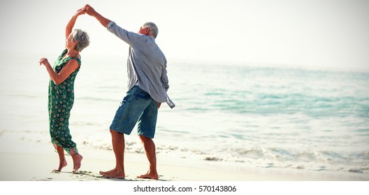 Una pareja mayor bailando en la playa en un día soleado
