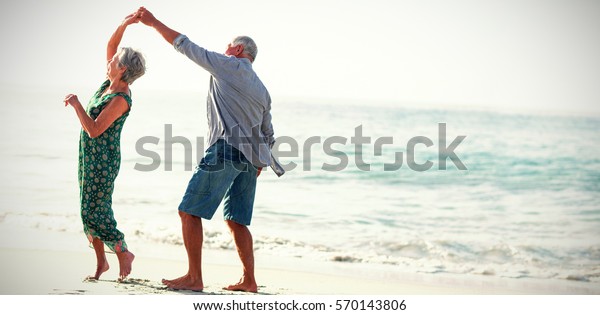 Senior couple dancing at beach on sunny day