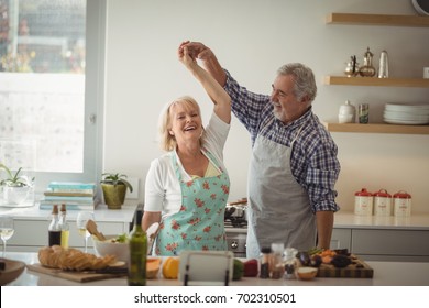 Senior Couple Dancing In Kitchen At Home