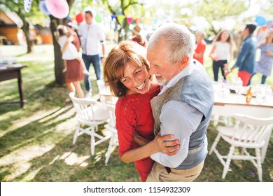 A Senior Couple Dancing On A Garden Party Outside In The Backyard.