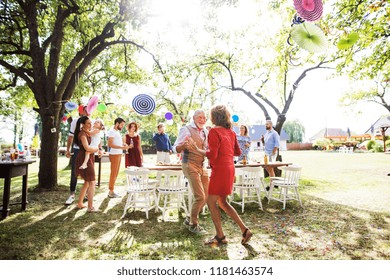 A Senior Couple Dancing On A Garden Party Outside In The Backyard.